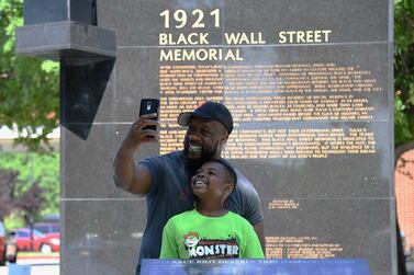 TULSA, OK - JUNE 19: A father and son take a selfie at the Black Wall Street Memorial during the Juneteenth Festival in the Greenwood District on June 19, 2021 in Tulsa, Oklahoma.  Juneteenth celebrations, now recognized as a federal holiday, are taking place around the country in recognition of the emancipation of African-American slaves.    Michael B.  Thomas / Getty Images / AFP
