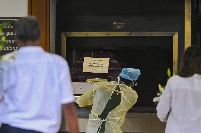 A worker places the coffin of Sri Lanka's former foreign minister Mangala Samaraweera, who died today due to Covid-19, in the furnace to be cremated at Colombo's main cemetery. AFP