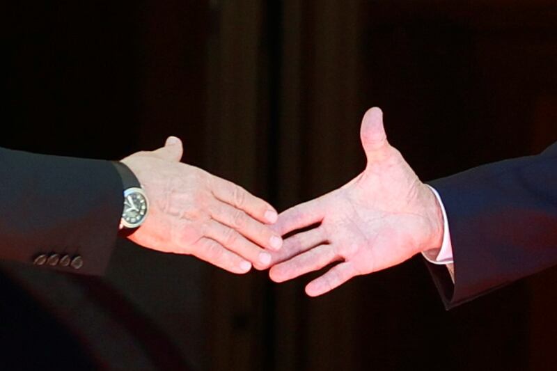 Joe Biden and Vladimir Putin shake hands. Reuters