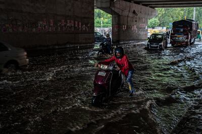 A man pushes his scooter through a waterlogged road after it rained in New Delhi, India, Thursday, Sept.  22, 2022.  (AP Photo / Altaf Qadri)
