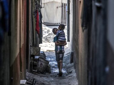 A Palestinian boy carries a toddler in Deir El Balah in the central Gaza Strip on May 15. AFP