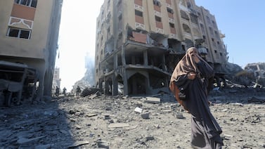 A Palestinian woman walks in front of a damaged residential buildings in Hamad City. Reuters