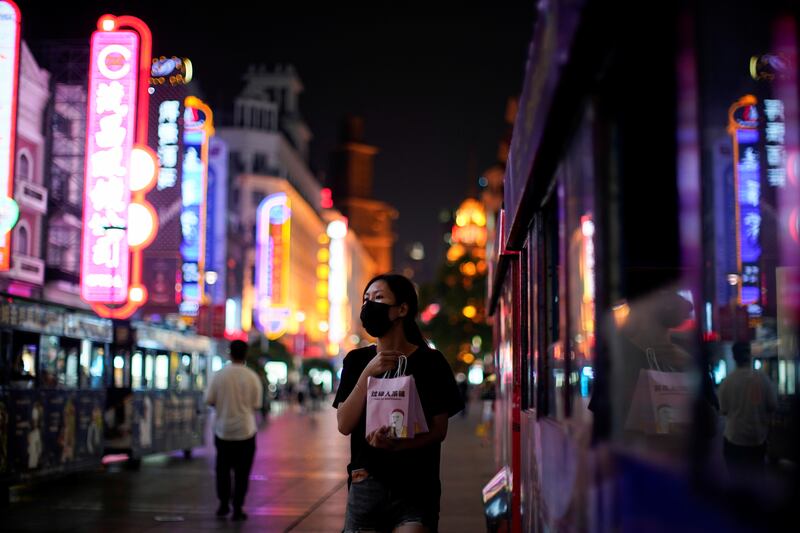 A woman wearing a protective mask walks on a street, following new cases of Covid-19, in Shanghai, China. Reuters