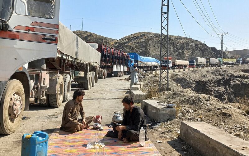 Men sit near a queue of trucks loaded with supplies to leave for Afghanistan, after Taliban authorities have closed the main border crossing in Torkham, Pakistan February 21, 2023.  REUTERS / Shahid Shinwari