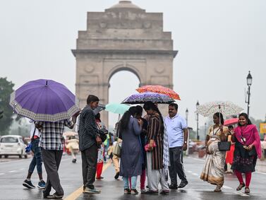 People use umbrellas as they visit they newly inaugurated central vista project near India Gate during a rainfall in New Delhi in September 23, 2022.  (Photo by Money SHARMA  /  AFP)