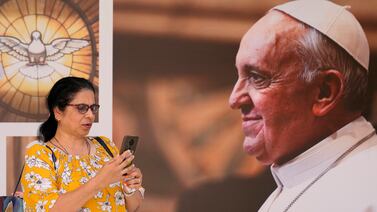 A woman speaks on her mobile phone, as she stands in front of a portrait of Pope Francis,  at Sacred Heart church, in Manama, Bahrain, Wednesday, Nov.  2, 2022.  Pope Francis is making the November 3-6 visit to participate in a government-sponsored conference on East-West dialogue and to minister to Bahrain's tiny Catholic community, part of his effort to pursue dialogue with the Muslim world.  (AP Photo / Hussein Malla)