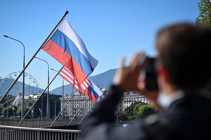 A man takes a picture with of Russian and US flags on the Mont-Blanc bridge in Geneva. AFP
