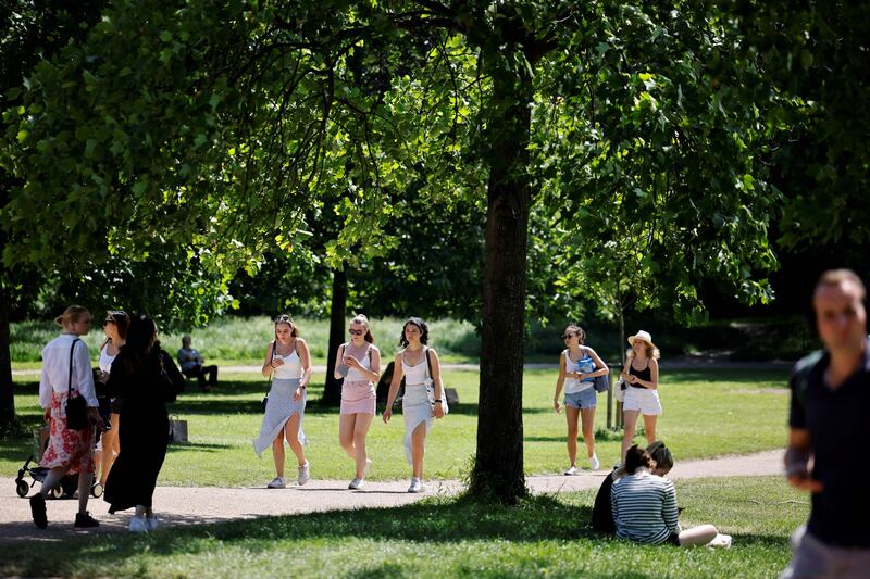 People walk in the sunshine in Hyde Park in London. The UK government has delayed the full lifting of coronavirus restrictions in England owing to a surge of infections caused by the Delta variant. AFP