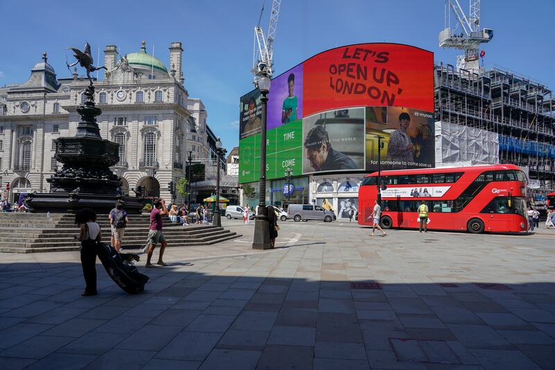 People walk in a quiet Piccadilly Circus, central London. The planned relaxation of coronavirus restrictions in England will be delayed as a result of the spread of the Delta variant first identified in India. AP