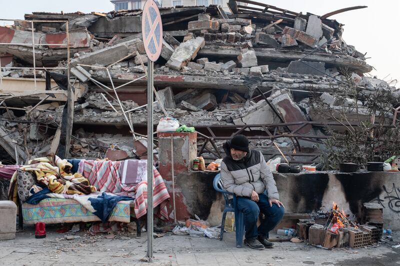 HATAY, TURKEY - FEBRUARY 13: A man sits near a collapsed building as she waits news from her loved ones on February 13, 2023 in Hatay, Turkey. A 7.8-magnitude earthquake hit near Gaziantep, Turkey, in the early hours of Monday, followed by another 7.5-magnitude tremor just after midday. The quakes caused widespread destruction in southern Turkey and northern Syria and were felt in nearby countries. (Photo by Burak Kara / Getty Images)