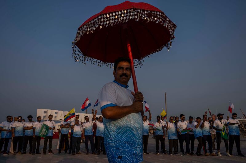 Indian football fans, part of the Thrissur Jilla Sauhrudavedi (TSJV) organization, a Keralite community, gather in front of the official FIFA World Cup Countdown Clock on Doha's corniche to celebrate 30 days to go until the start of the World Cup, in Qatar, Friday, Oct.  21, 2022.  (AP Photo / Nariman El-Mofty)