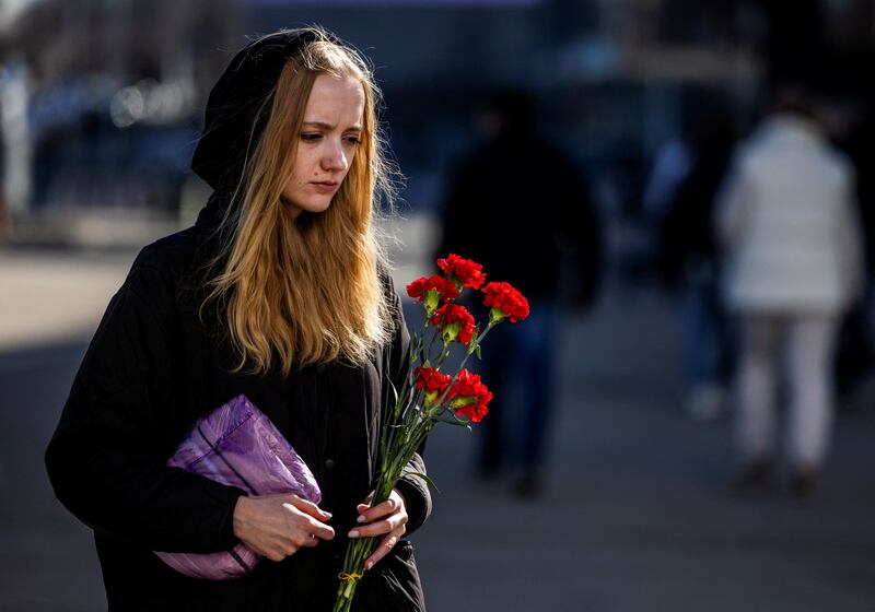 A woman walks to lay flowers at a makeshift memorial near the Crocus City Hall following last Friday's deadly attack on the concert venue in Moscow. Reuters