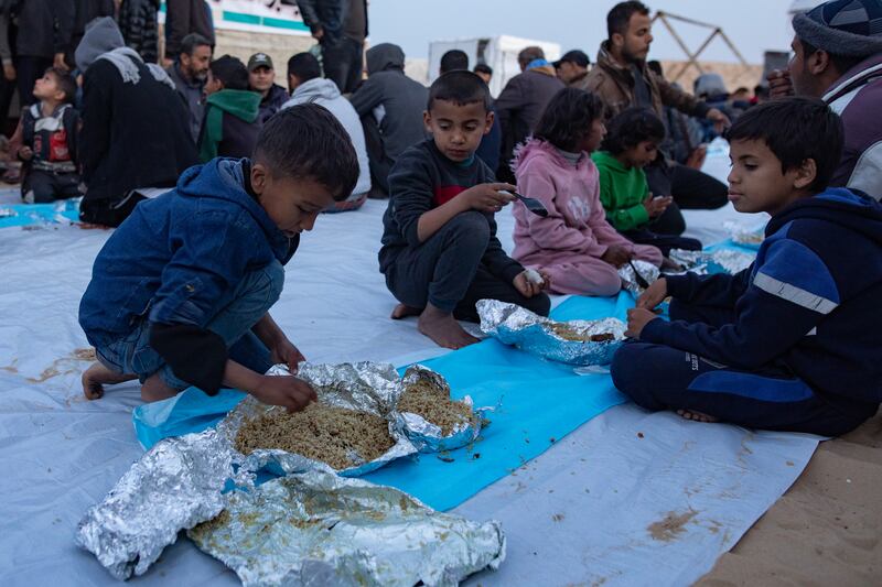 Displaced Palestinians break their fast together during the holy month of Ramadan at a collective Iftar meal organized by a youth volunteer group in a makeshift camp on the Egyptian border near Rafah, in the southern Gaza Strip, 26 March 2024. EPA