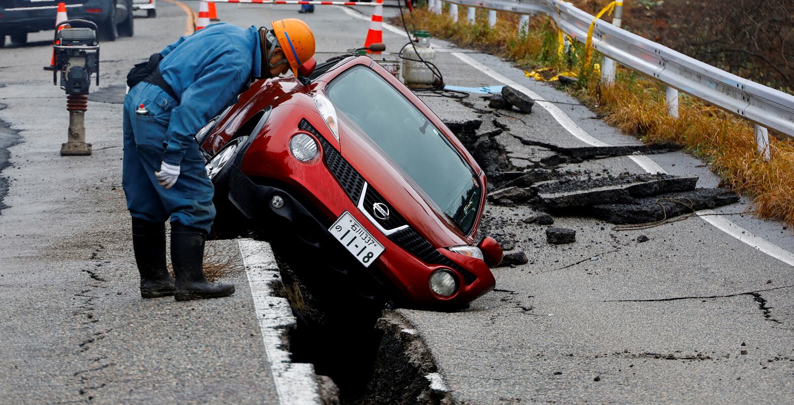A worker looks at a car stuck on a broken road in the aftermath of an earthquake, near Anamizu, Japan, January 3, 2024.  REUTERS / Kim Kyung-Hoon     TPX IMAGES OF THE DAY